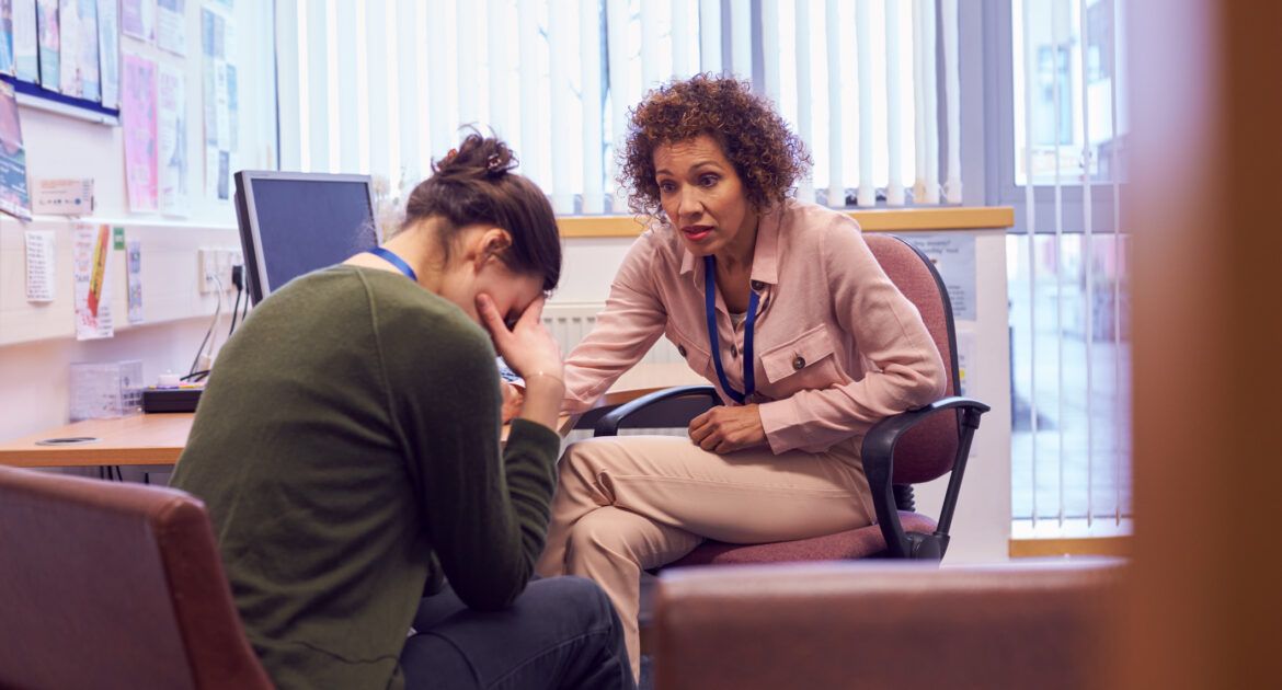 Female College Student Meeting With Campus Counselor Discussing Mental Health Issues