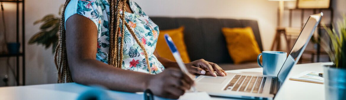 African American female student studying from home and taking notes from professor