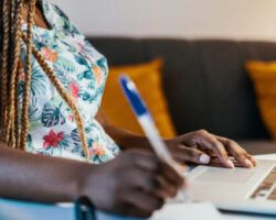 African American female student studying from home and taking notes from professor