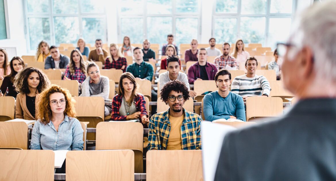 Large group of college students listening to their professor on a class.