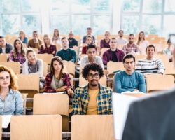 Large group of college students listening to their professor on a class.