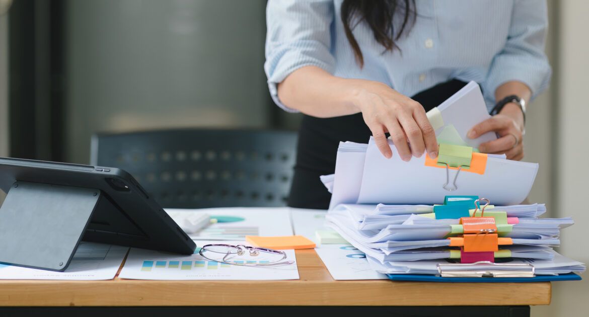 A businesswoman is sifting through stacks of paper files workload