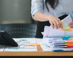 A businesswoman is sifting through stacks of paper files workload