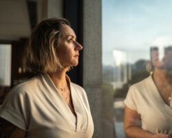 Contemplative mature woman looking through the window in reflection