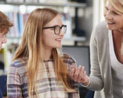 Female Teacher Working With College Students In Library