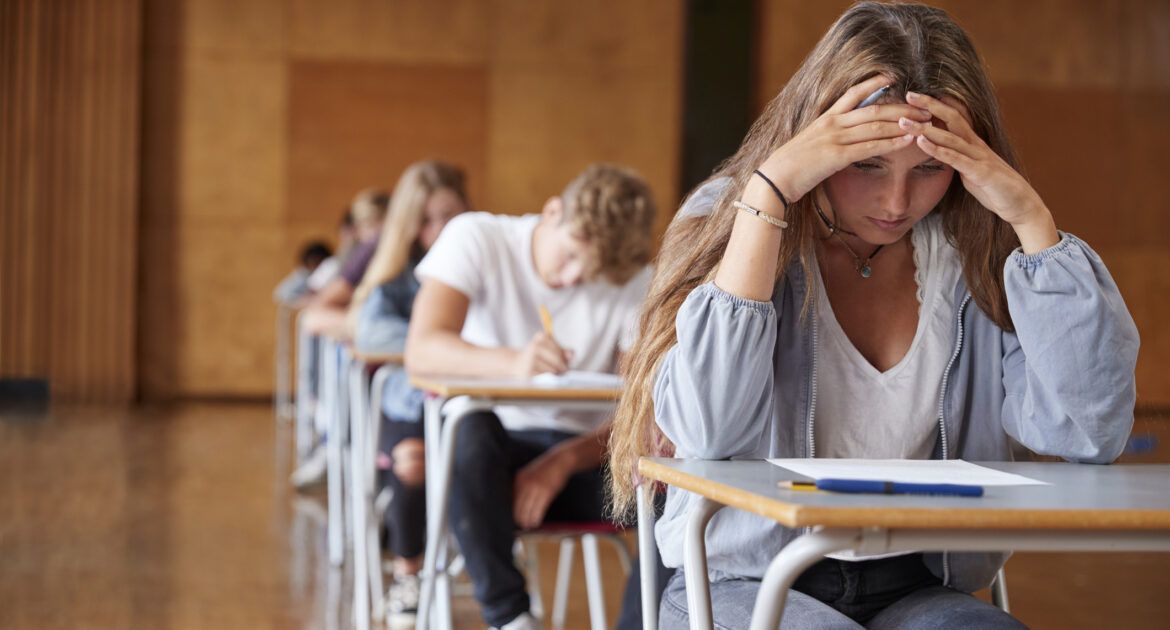 Anxious Teenage Student Sitting Examination In School Hall