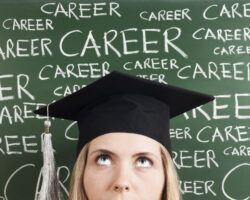 Woman in mortarboard standing in front of chalk words