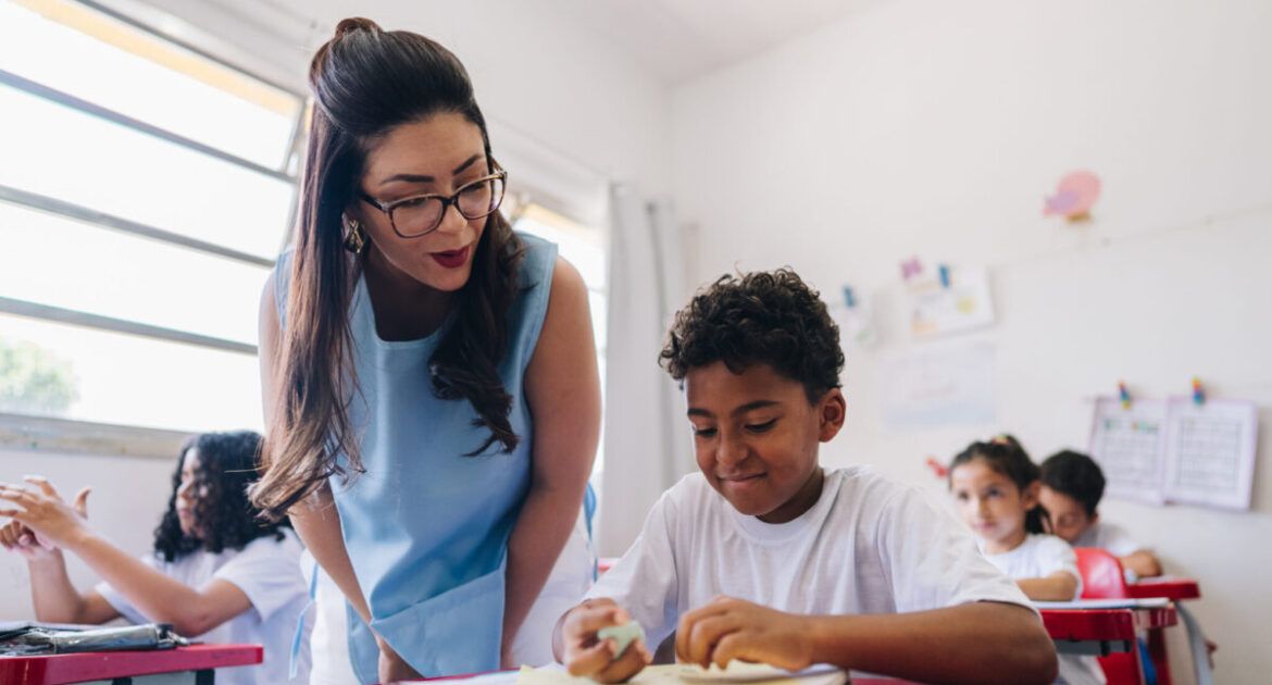 Teacher teaching her student on classroom at school