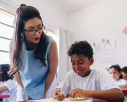 Teacher teaching her student on classroom at school