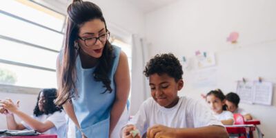 Teacher teaching her student on classroom at school