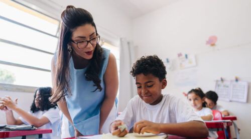 Teacher teaching her student on classroom at school