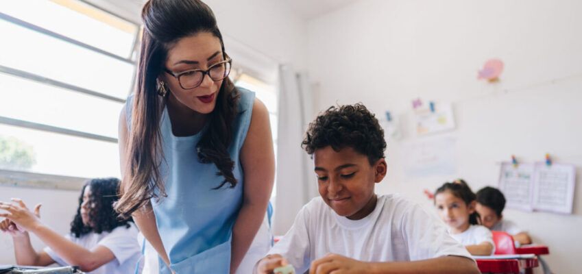 Teacher teaching her student on classroom at school