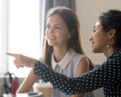Female intern listening to mentor explaining computer task