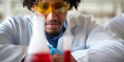 A young male chemistry student observes a chemical in a test tube in the laboratory.