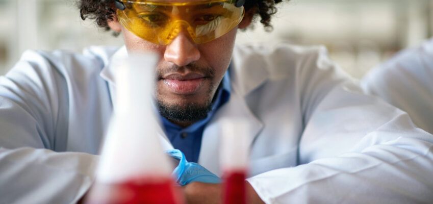 A young male chemistry student observes a chemical in a test tube in the laboratory.