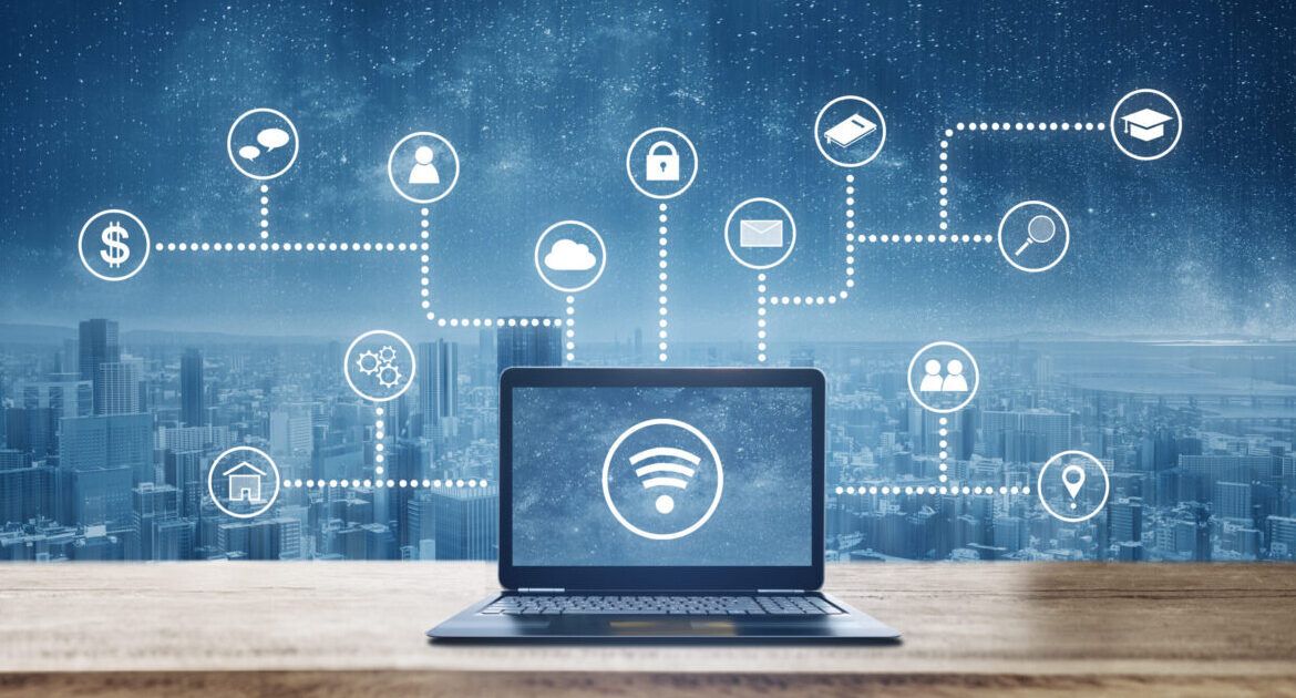 Computer laptop on wooden desk with wireless and application programming and social media icons. Internet networking and wireless technology