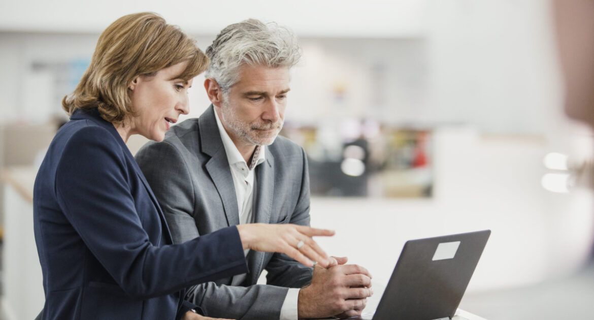 man and woman talking about learning at laptop