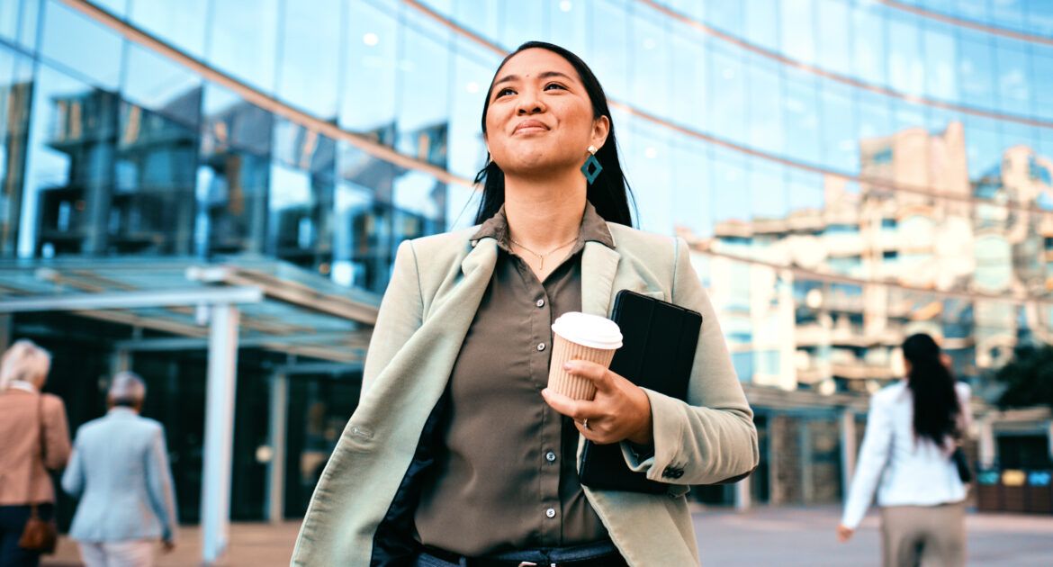 Confident Businesswoman Walking with Coffee Outside Modern Office Building