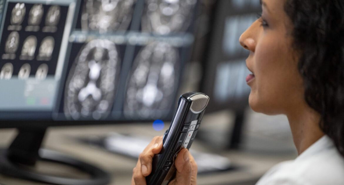 Female radiologist speaking into a dictation recorder while looking at MRI scan