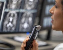 Female radiologist speaking into a dictation recorder while looking at MRI scan