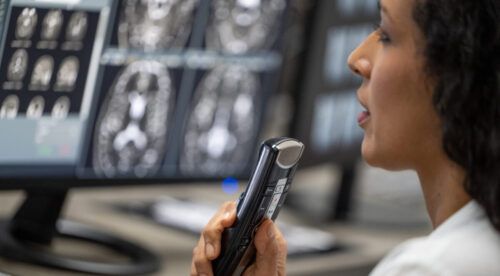 Female radiologist speaking into a dictation recorder while looking at MRI scan