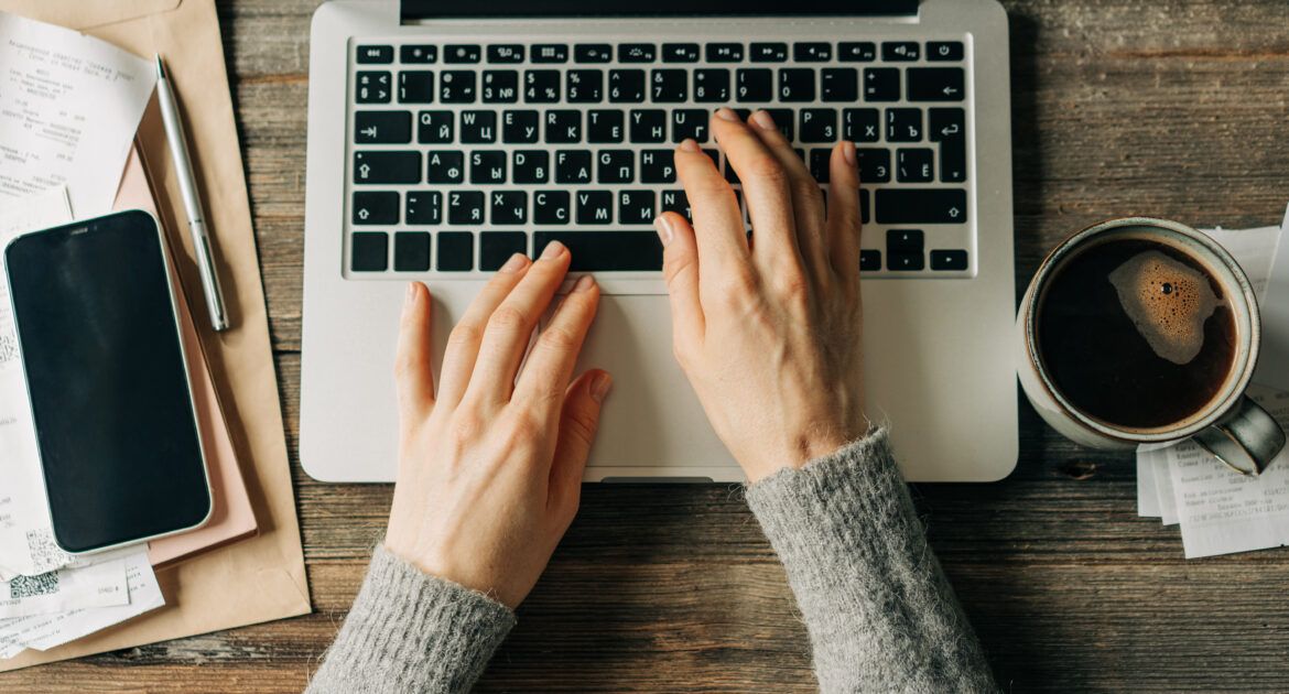 Top view of female hands typing on a laptop keyboard.