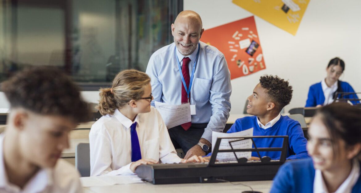 Male teacher interacting with group of students