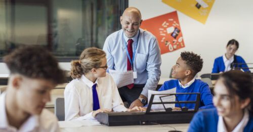 Male teacher interacting with group of students