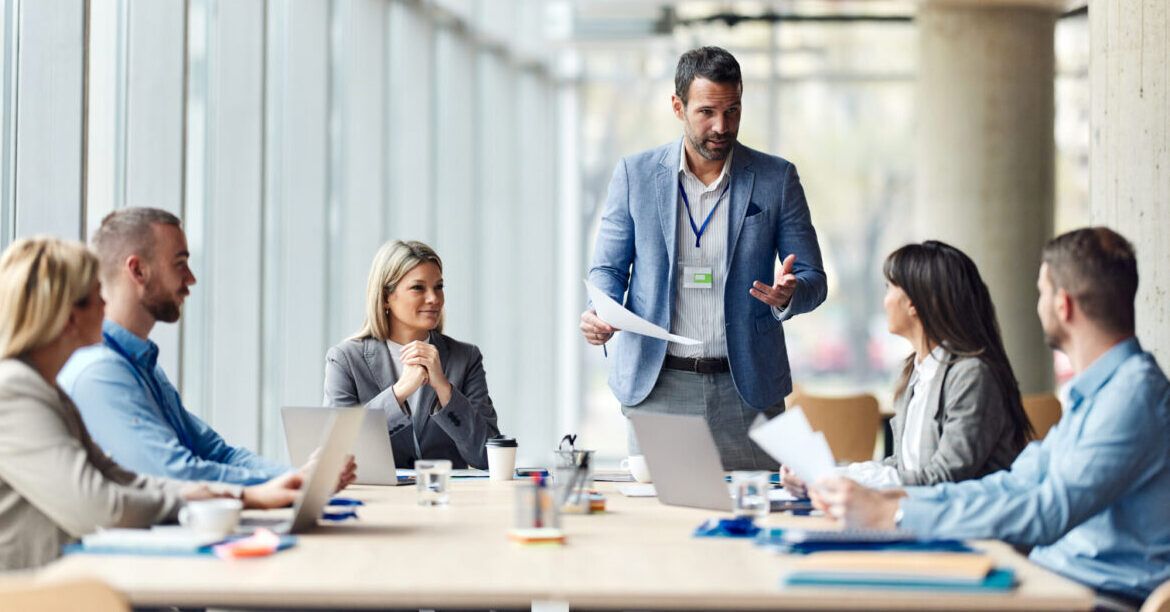 Male leader talking to his team about plans on a meeting in the office.