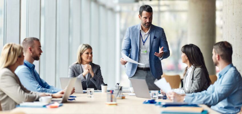 Male leader talking to his team about plans on a meeting in the office.