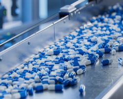 Blue Capsules on Conveyor at Modern Pharmaceutical Factory. Tablet and Capsule Manufacturing Process. Close up Shot of Medical Drug Production Line.