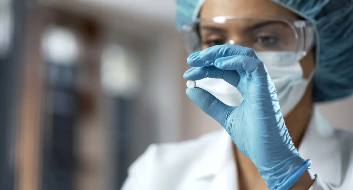 Female chemist looking at white pill, new medication testing in laboratory