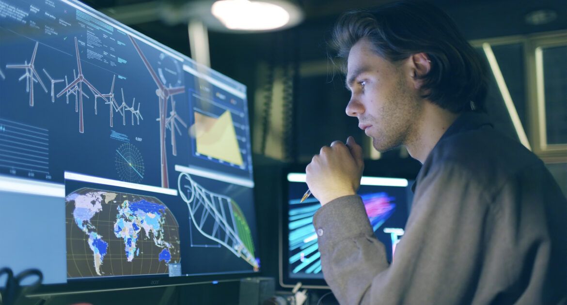 young male conducting research on wind turbines at a computer