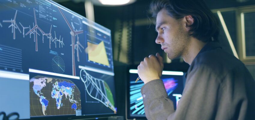 young male conducting research on wind turbines at a computer