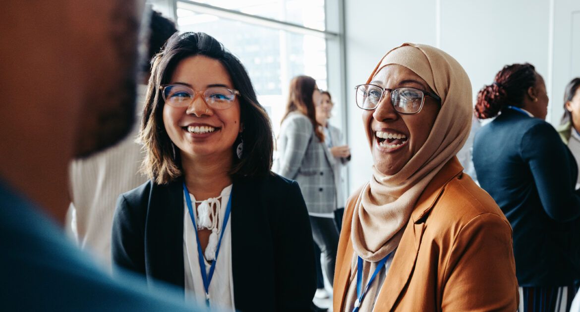 Female colleagues interacting at a corporate workshop with happy smiles and engaging conversations