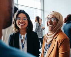 Female colleagues interacting at a corporate workshop with happy smiles and engaging conversations