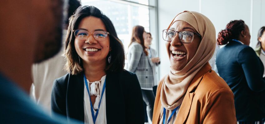 Female colleagues interacting at a corporate workshop with happy smiles and engaging conversations