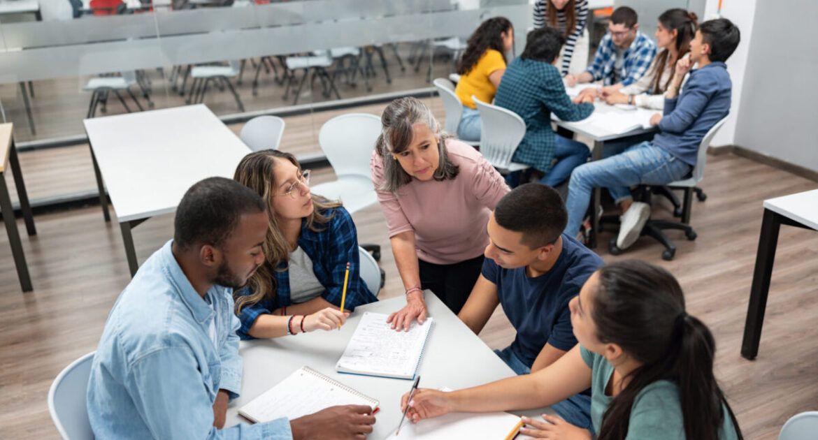 Teacher in class explaining something to a group of students