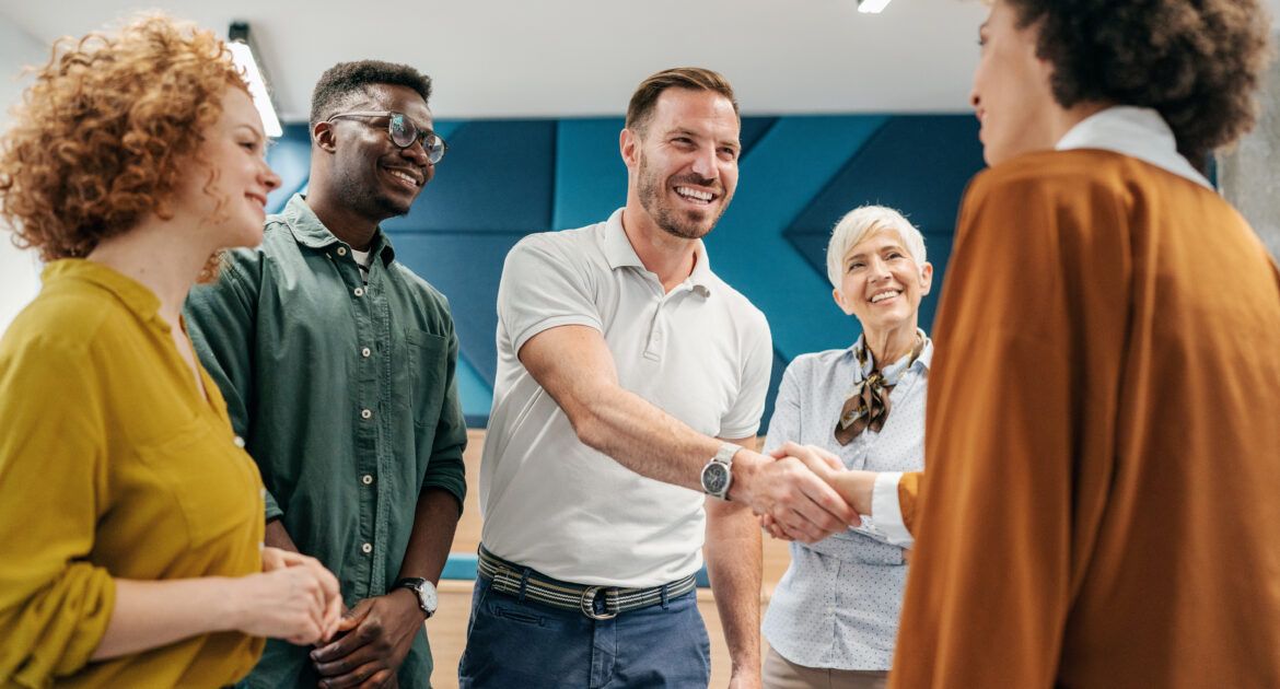 group of people shaking hands to welcome new colleague