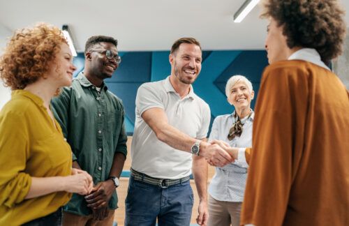 group of people shaking hands to welcome new colleague