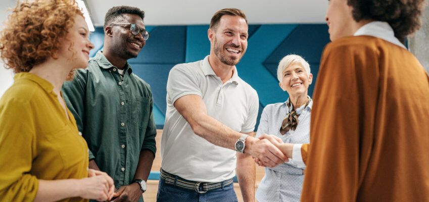 group of people shaking hands to welcome new colleague