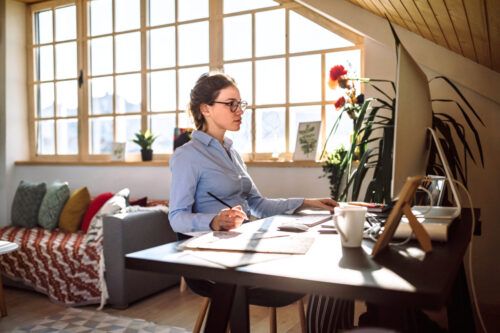 young woman sitting at her desk in front of pc at home